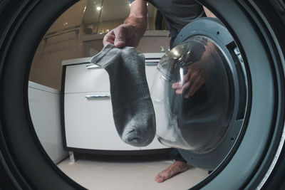 A man loads laundry into an automatic washing machine. view from the washing machine.