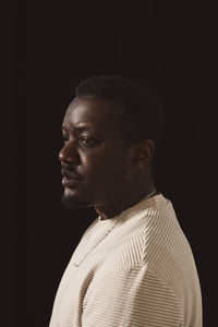 Contemplative man looking away by black background in studio