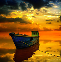 Fishing boat moored in sea against sky during sunset