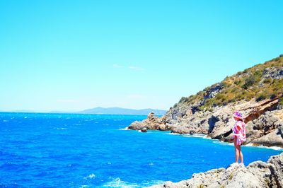 Rear view of man standing on rock against sea