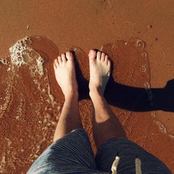 Low section of man standing on beach