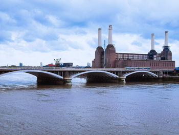 Arch bridge over river against sky in city