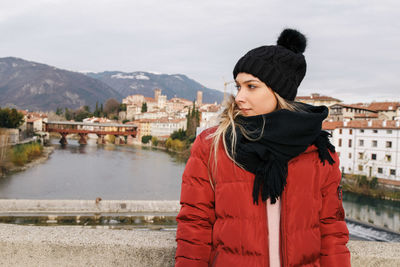 Young woman standing by built structure against sky