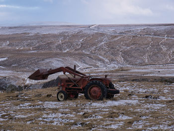 Tractor on field against sky during winter