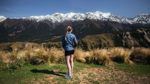 Rear view of woman standing on mountain against sky