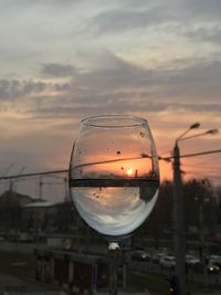 Close-up of glass against sky at sunset