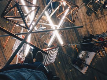 Low section of man on ladder over fluorescent lights at store