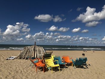 Deck chairs on beach against sky