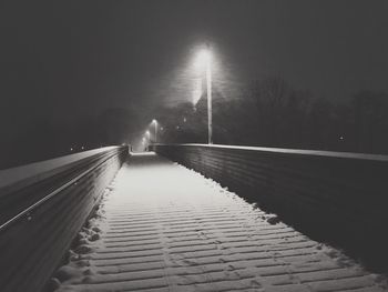 Illuminated bridge against sky at night during winter