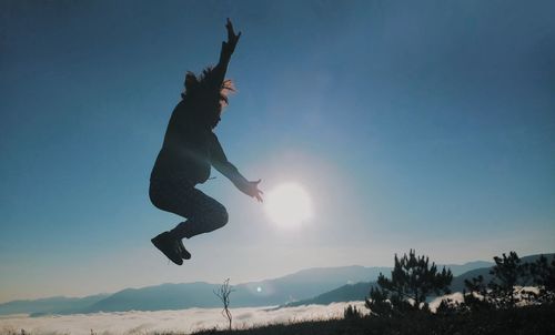 Low angle view of silhouette person jumping against sky