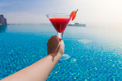 Woman holding drink in swimming pool