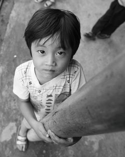 High angle portrait of cute boy holding pole on street