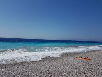 Scenic view of beach against clear blue sky