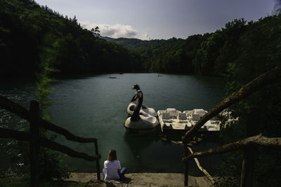 High angle view of woman sitting by lake in forest