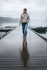 Full length of man standing on pier over lake against sky