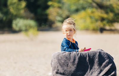 Portrait of cute girl standing by towel