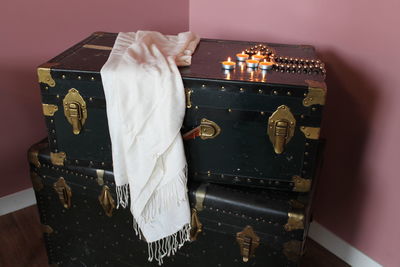 High angle view of white scarf and tea lights on antique suitcase