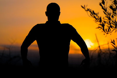 Silhouette man standing against orange sky