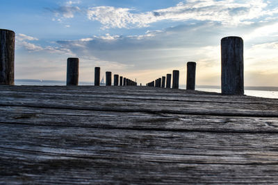 Wooden posts on beach against sky during sunset