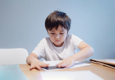 Boy looking away while sitting on table