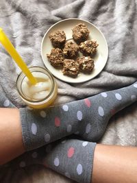 Low section of woman wearing socks while sitting by food in plate on bed