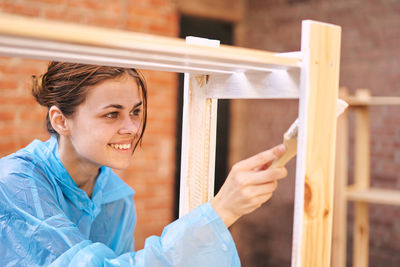 Portrait of smiling young woman looking through window