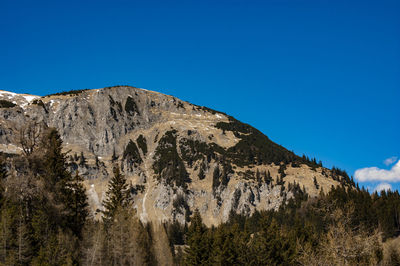 Low angle view of rocky mountain against clear blue sky