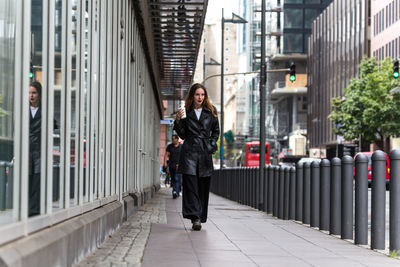 Full length of woman walking on sidewalk in city