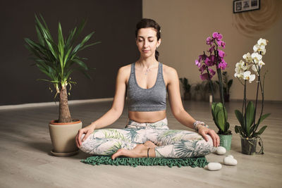 Woman doing meditation at yoga studio in the middle of flowers