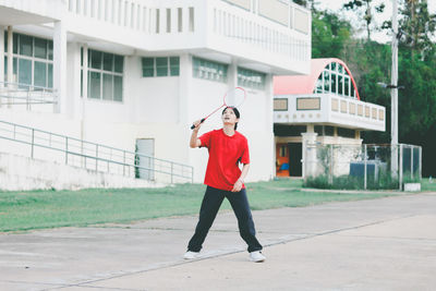 Young woman playing badminton while standing outdoors