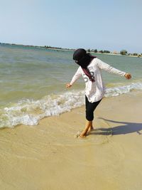 Full length of woman standing on beach against clear sky