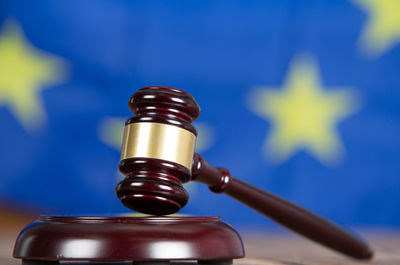 Close-up of gavel with hammer on table against european flag