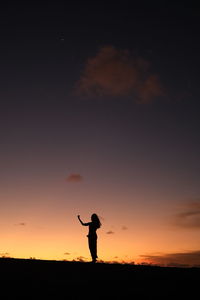 Silhouette man standing on field against sky during sunset