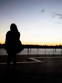 Silhouette woman standing on beach against clear sky during sunset