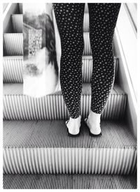 Low section of woman standing on escalator