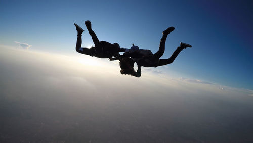 Sunset skydiving. 3-way skydive formation. free-fall man group jumping against clear sky aerial view