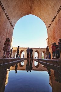 People standing by arch against clear sky