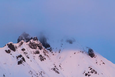 Low angle view of snowcapped mountains against clear blue sky