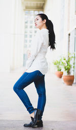 Side view of young woman posing on walkway by building