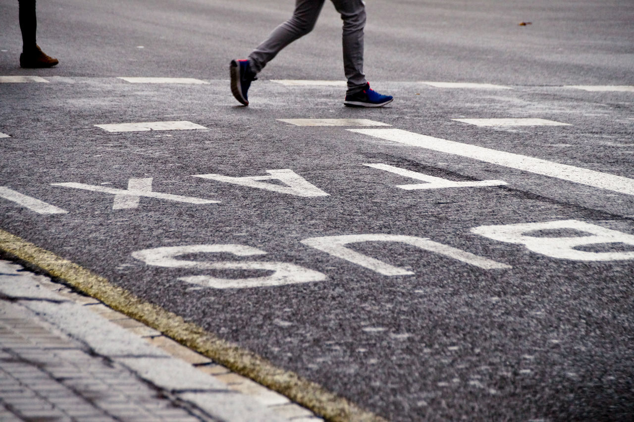 LOW SECTION OF PERSON WALKING ON ZEBRA CROSSING