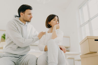 Man consoling woman sitting at home