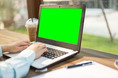 Close-up of businesswoman using laptop on table at sidewalk cafe