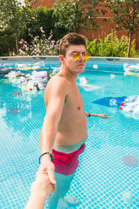 Man wearing sunglasses standing by swimming pool