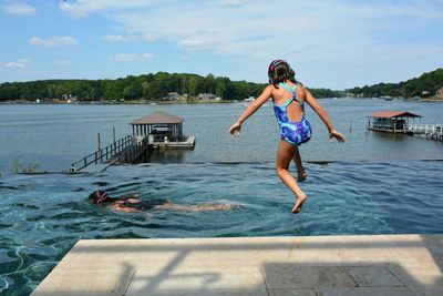 Rear view full length of girl jumping in lake