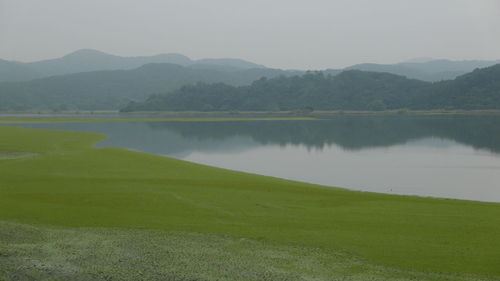 Scenic view of lake by mountains against sky