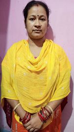 Portrait of woman standing against yellow wall