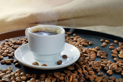 Cup of aromatic coffee and roasted coffee beans, close-up