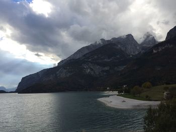 Scenic view of sea and mountains against cloudy sky