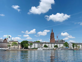 View of buildings by river against sky in city