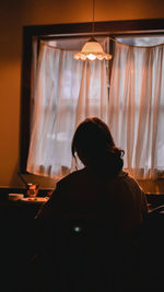 Rear view of woman sitting at home